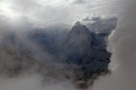 view on snowy mountains peak Caucasus through cloudsの写真素材
