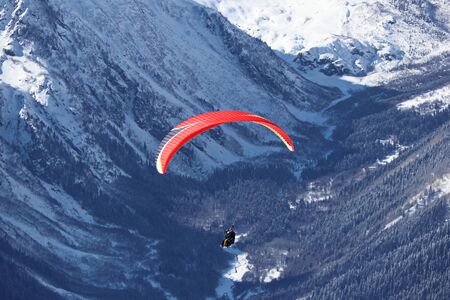 paraplane flying over snowy Caucasus mountains and sunny blue skyの写真素材