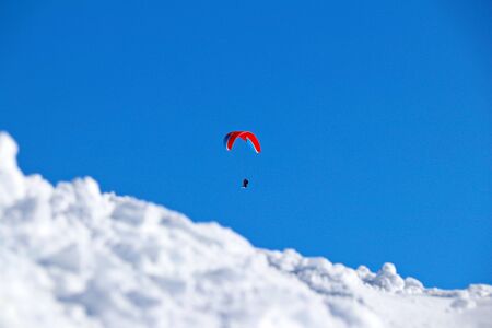 paraplane flying over snowy Caucasus mountains and sunny blue skyの写真素材