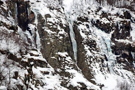 sheer cliff covered with snow and big iciclesの写真素材