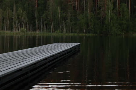 Wooden pier on a forest lake at dusk.