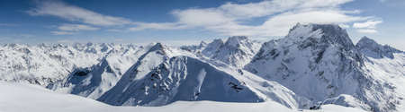 Panoramic view of snowy mountains peaks in the clouds blue sky Caucasusの写真素材