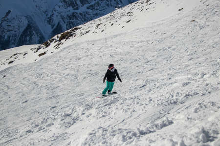 girl on a snowboard rides down the side of the mountainの写真素材