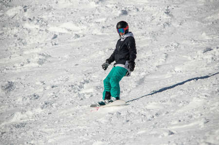 girl on a snowboard rides down the side of the mountainの写真素材
