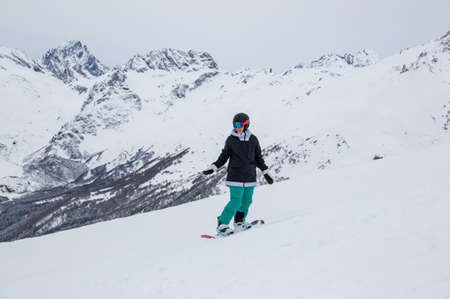 girl on a snowboard rides down the side of the mountainの写真素材