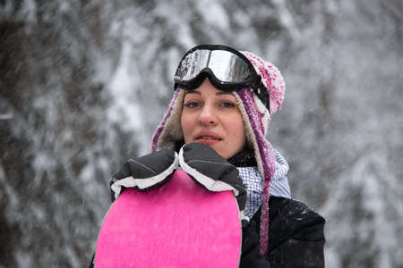 Girl with a snowboard in the forest in the mountains and the snowfallの写真素材