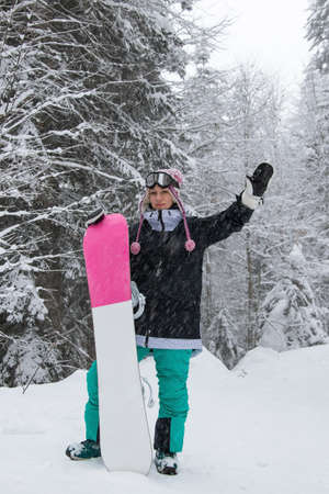 Girl with a snowboard in the forest in the mountains and the snowfallの写真素材