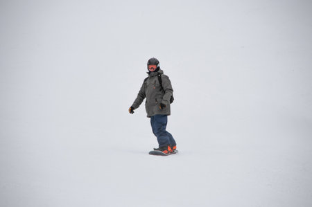 Man on a snowboard rides down the side of the mountainの写真素材