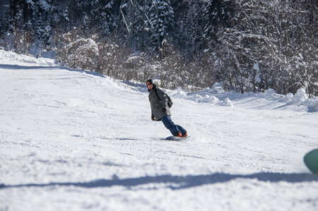 Man on a snowboard rides down the side of the mountainの写真素材