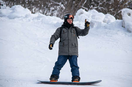 Man on a snowboard rides down the side of the mountainの写真素材