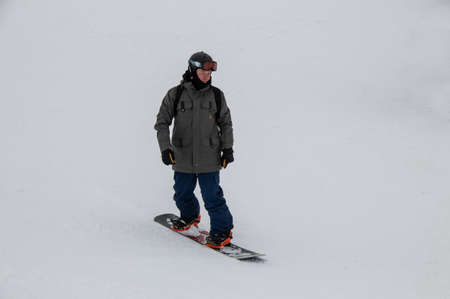 Man on a snowboard rides down the side of the mountainの写真素材
