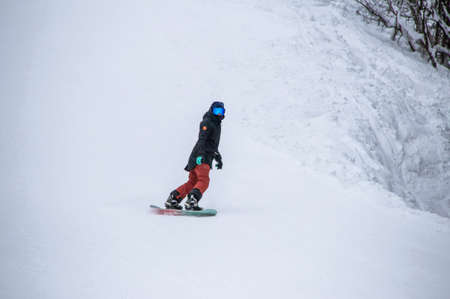 girl on a snowboard rides down the side of the mountainの写真素材