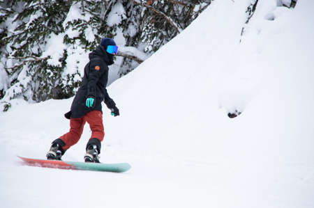 girl on a snowboard rides down the side of the mountainの写真素材