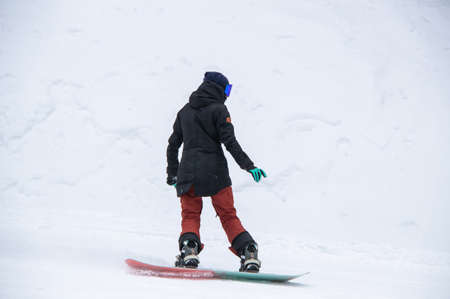 girl on a snowboard rides down the side of the mountainの写真素材