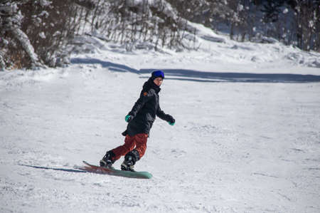 girl on a snowboard rides down the side of the mountainの写真素材