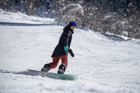 girl on a snowboard rides down the side of the mountainの写真素材