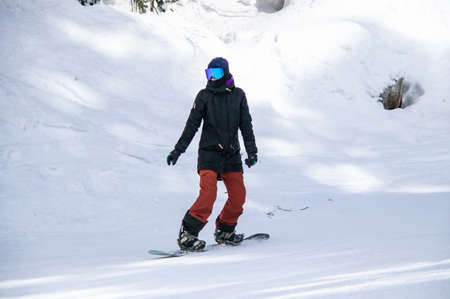 girl on a snowboard rides down the side of the mountainの写真素材