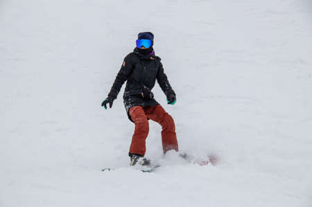 girl on a snowboard rides down the side of the mountainの写真素材