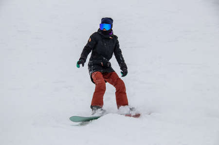 girl on a snowboard rides down the side of the mountainの写真素材