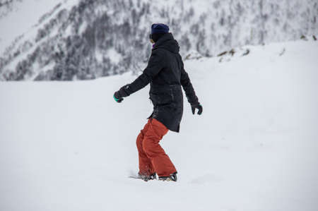 girl on a snowboard rides down the side of the mountainの写真素材