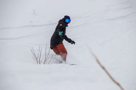 girl on a snowboard rides down the side of the mountainの写真素材