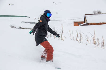 girl on a snowboard rides down the side of the mountainの写真素材