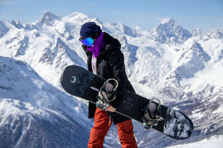 Portrait of a girl with snowboard on top of a snowy mountain.の写真素材