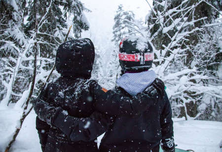 Two girls with a snowboards in the forest in the mountains and the snowfallの写真素材