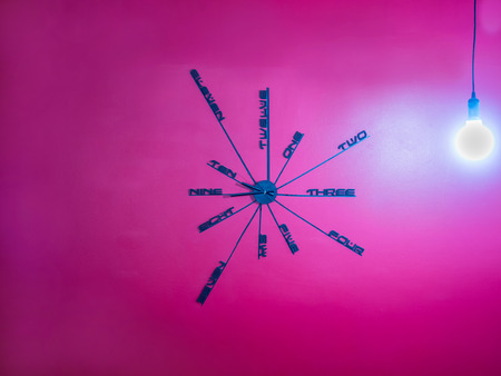 Creative design wall clock on red concrete wall and bulbの写真素材