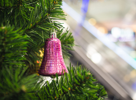Pink ring bell hanging on Christmas tree with blur background, selective focus