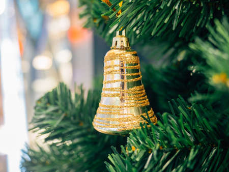 Golden ring bell hanging on Christmas tree with blur background, selective focus