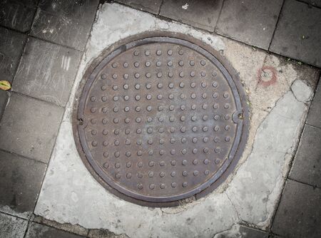 Rusty circle iron manhole cover on the concrete floorの写真素材