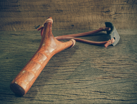 Thai wooden slingshot or catapult on the wooden table with copy space (vintage tone)の写真素材