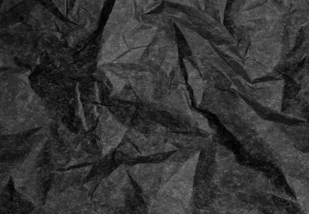 Crumpled black paper with coarse wrinkles and fine texture, forming a vintage background の写真素材