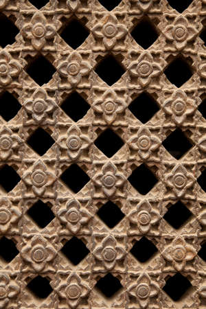 Carved stone latticework with flowers and squares design creating a perforated wall 