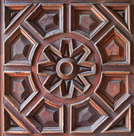 Beautiful pattern with a flower on the center carved on the surface of a wooden door の写真素材