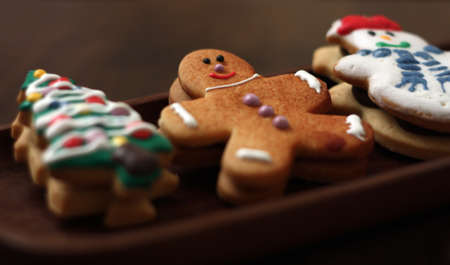 Wooden plate with three Christmas cookies: A Gingerbread Man, A Christmas Tree and a Snowman.