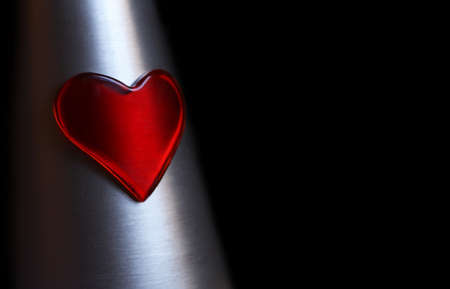 Red plastic heart on silver metalの写真素材