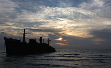 Silhouette of old ship in the sunset offshore of Kish Islandの写真素材