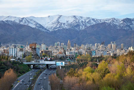 Tehran skyline and greeneries in front of snow covered Alborz Mountains as viewed from atop of Nature Bridge.の写真素材