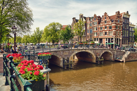 Amsterdam colorful houses, geranium flowers and triple arch bridge at the intersection between Prinsengracht and Brouwersgracht Canals.のeditorial素材
