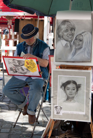 PARIS, FRANCE - JUNE 07, 2010: Parisian artist drawing a caricature in Place du Tertre of Montmartre, which is a famous hangout for buskers and artists painting landscapes and tourist portraits.のeditorial素材