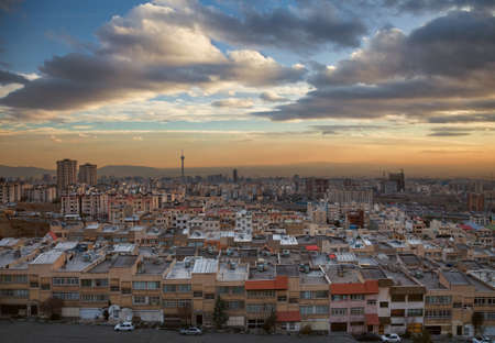 Skyline of Tehran with Milad Tower, residential and commercial buildings at a dramatic sunset with...