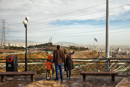 TEHRAN, IRAN - FEBRUARY 11, 2015: Iranian family with their son staring at skyline of Tehran from a...