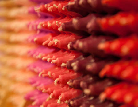 Colorful stick candles with orange and red tonality, arranged in shelves and sorted by color in a candle shop.の写真素材