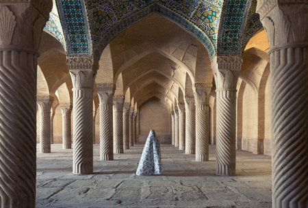 Woman in veil standing between spirally carved columns of Shabestan of Vakil Mosque in Shiraz city of Iran.のeditorial素材