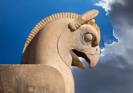 Statue of Huma or Homa bird as decorative column capital in Persepolis of Shiraz against blue sky with white clouds.の写真素材