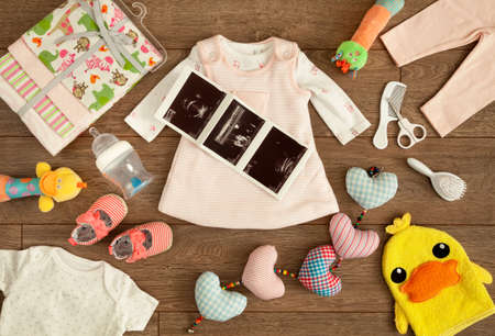Required accessories of a newborn infant in the expecting period before her born accompanied by her sonography report, shot from above in a tabletop flat lay arrangement.の写真素材