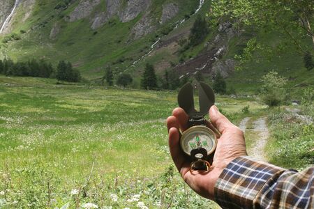 man hand holding an orientation compass with beautiful mountain scenery on the background with copy space for your textの写真素材