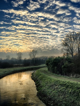 Sunset sky with altocumulus clouds reflected in the water of the riverの写真素材